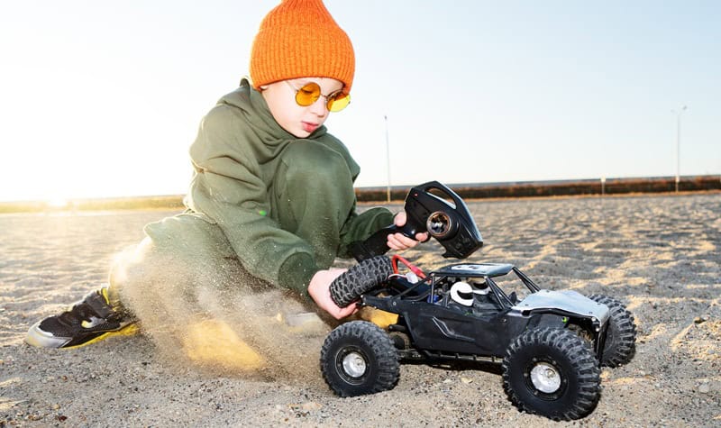 Voiture télécommandée RC crawler tout-terrain - Enfant jouant sur sable au coucher du soleil - Loisir famille hobby grade APEX RC | APEX RC